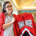 首席海豹老师萨拉·马丁站在高中拿着一件运动衫 