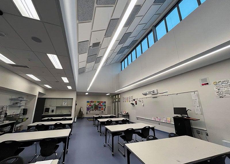 一间大教室里有几张桌子和一块带有横窗和顶灯的白板